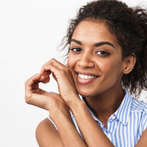 Smiling african american woman making a heart gesture on white background.