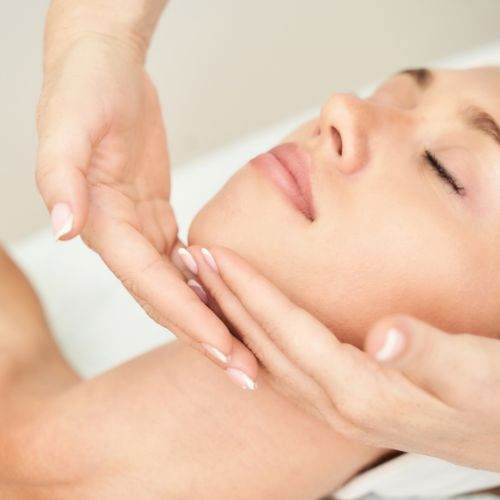 A woman getting a facial massage at a spa.